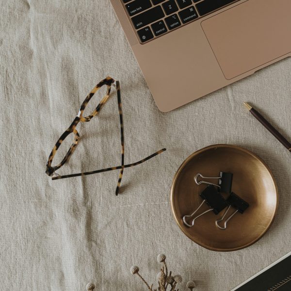 Flatlay laptop computer, glasses, brass plate, women's fashion accessories on neutral linen cloth. Top view minimalist aesthetic work, business concept